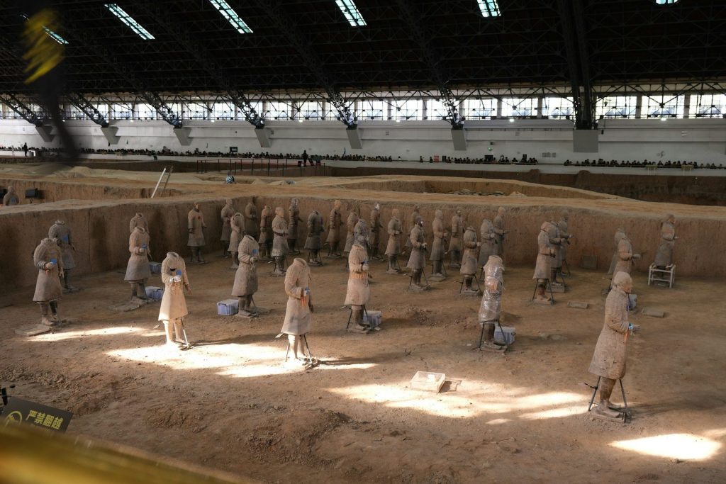 Terracotta warriors in a large excavation site.