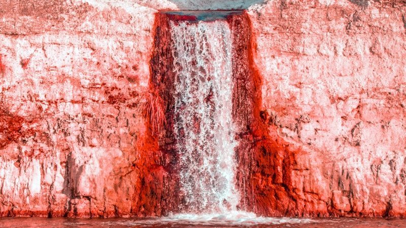 a large waterfall is coming out of the side of a cliff