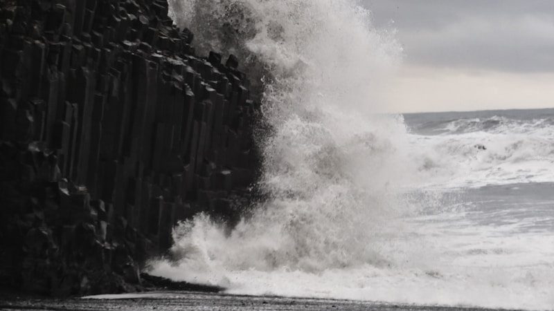 a large wave crashing into a rocky beach