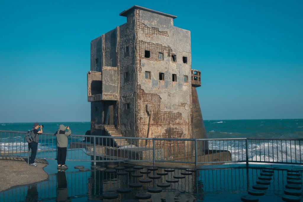 Old concrete structure on the coast with two people observing