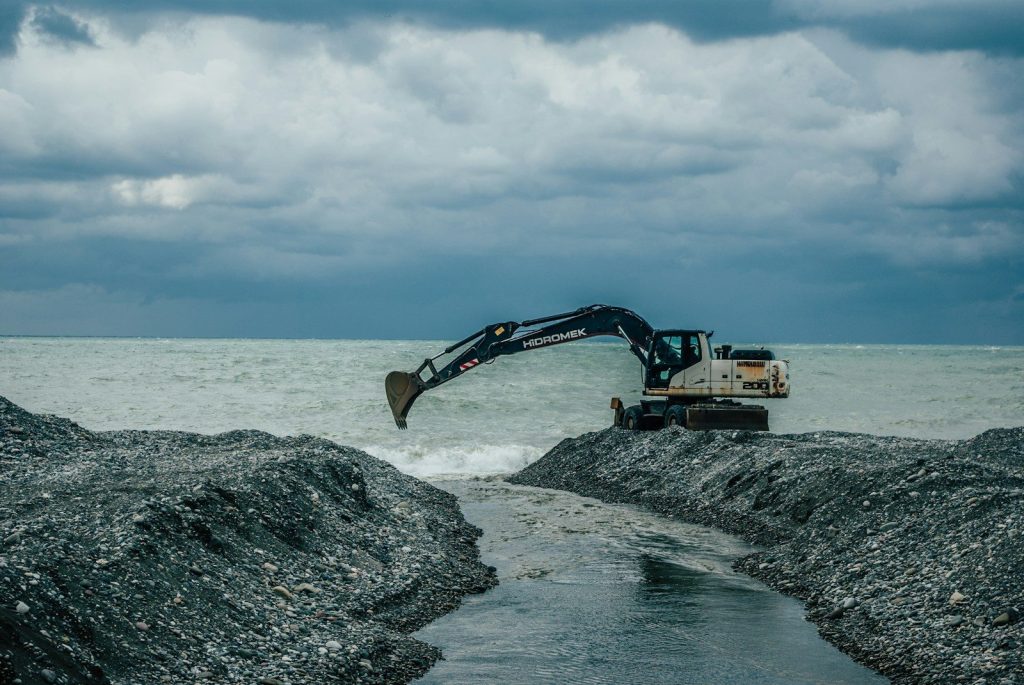 a bulldozer digging through the rocks in the ocean