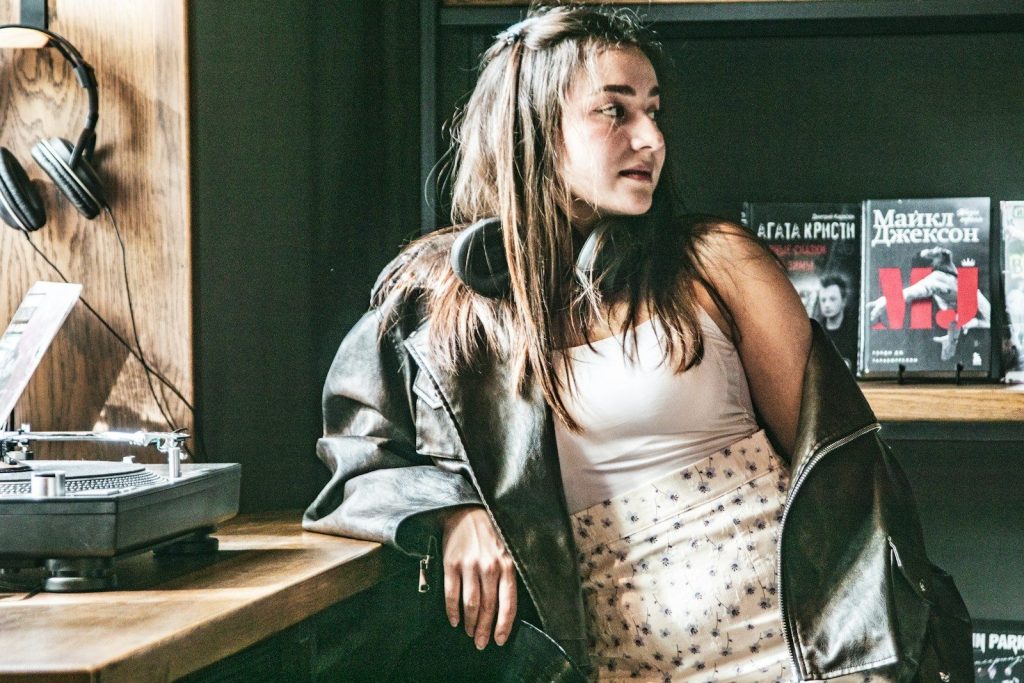 Young woman in leather jacket near record player