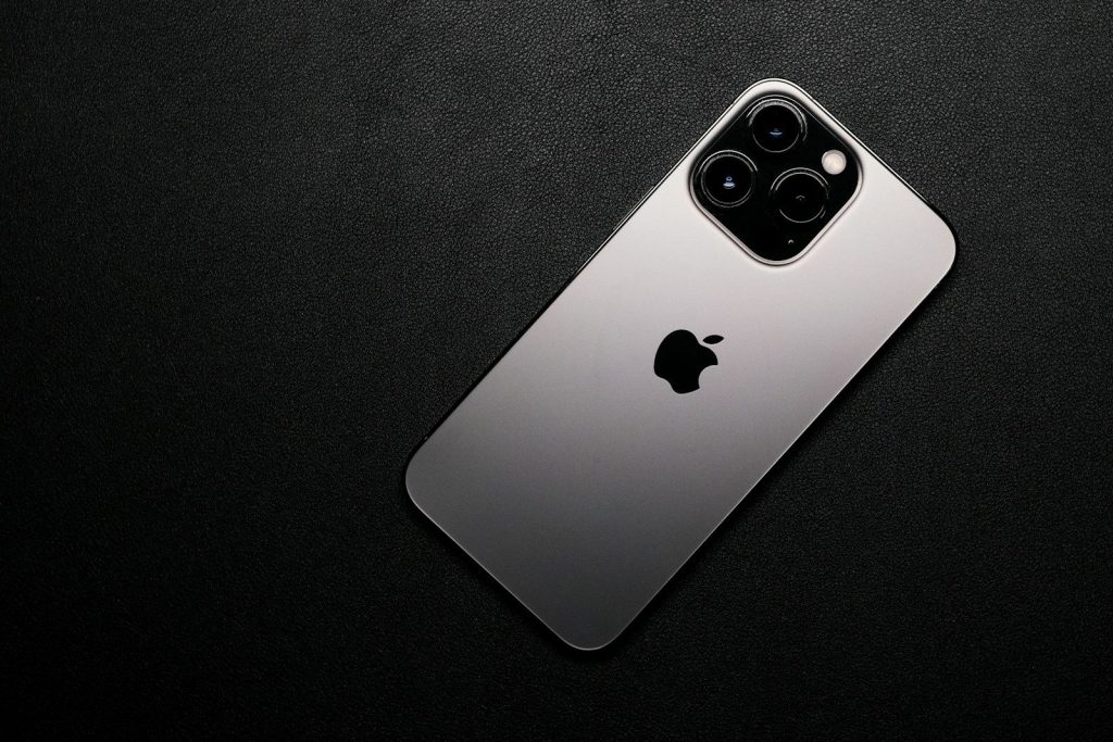 a close up of a silver iphone on a black surface