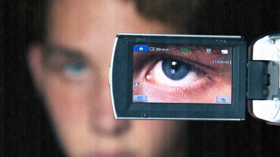a woman holding up a cell phone with a picture of an eye on it