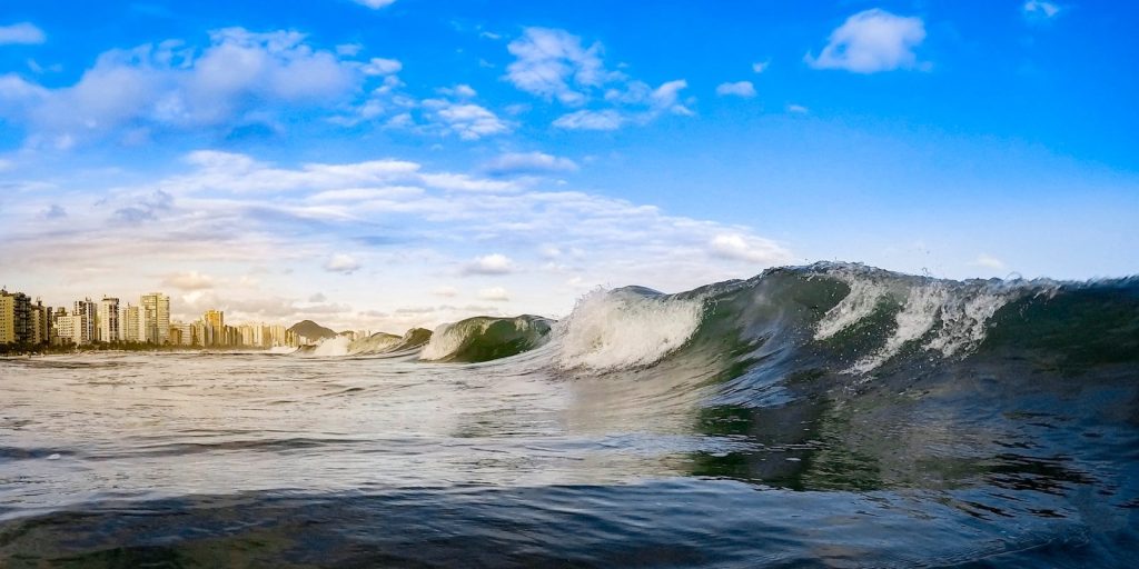 ocean waves crashing on rocks under blue sky and white clouds during daytime