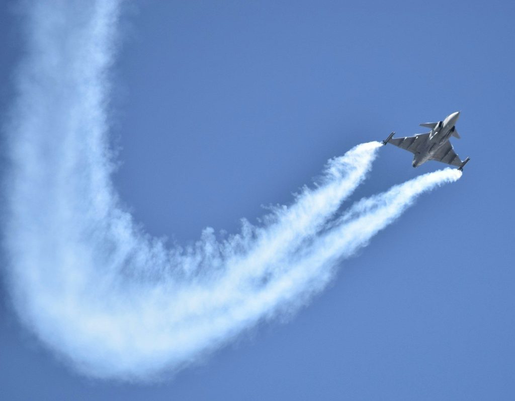 a fighter jet flying through a blue sky