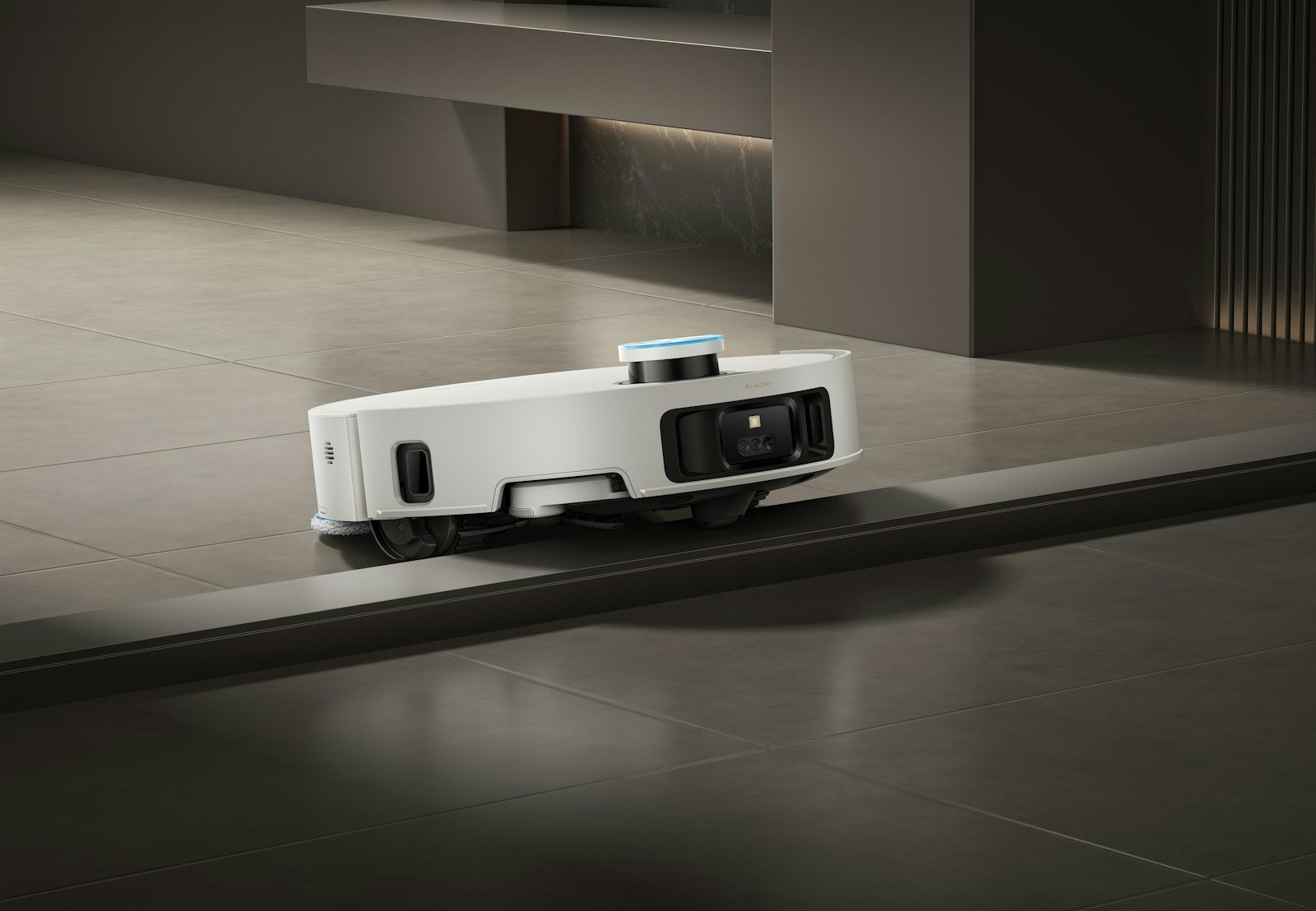 A white robot vacuum cleaner navigates a floor transition.