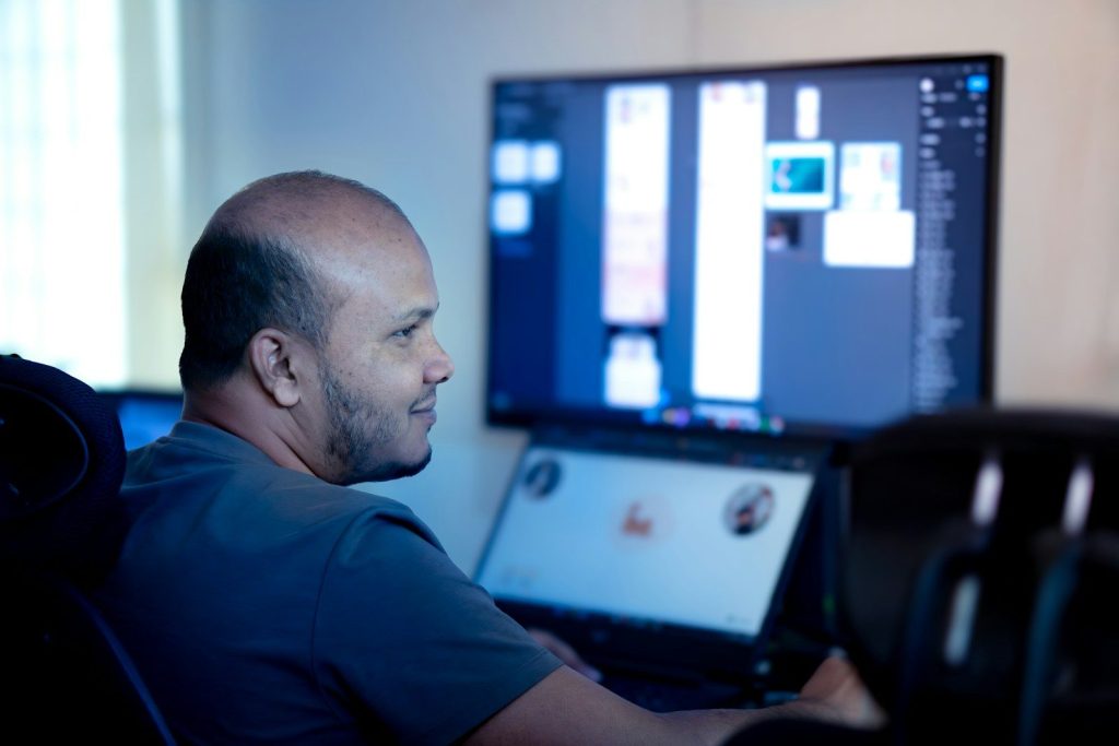 Man working on computer and large monitor