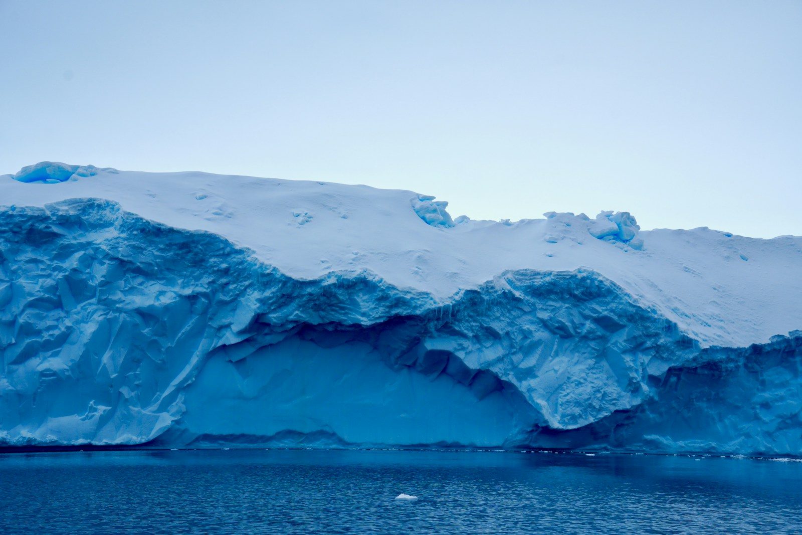 Massive iceberg with blue ice and snow in the ocean.