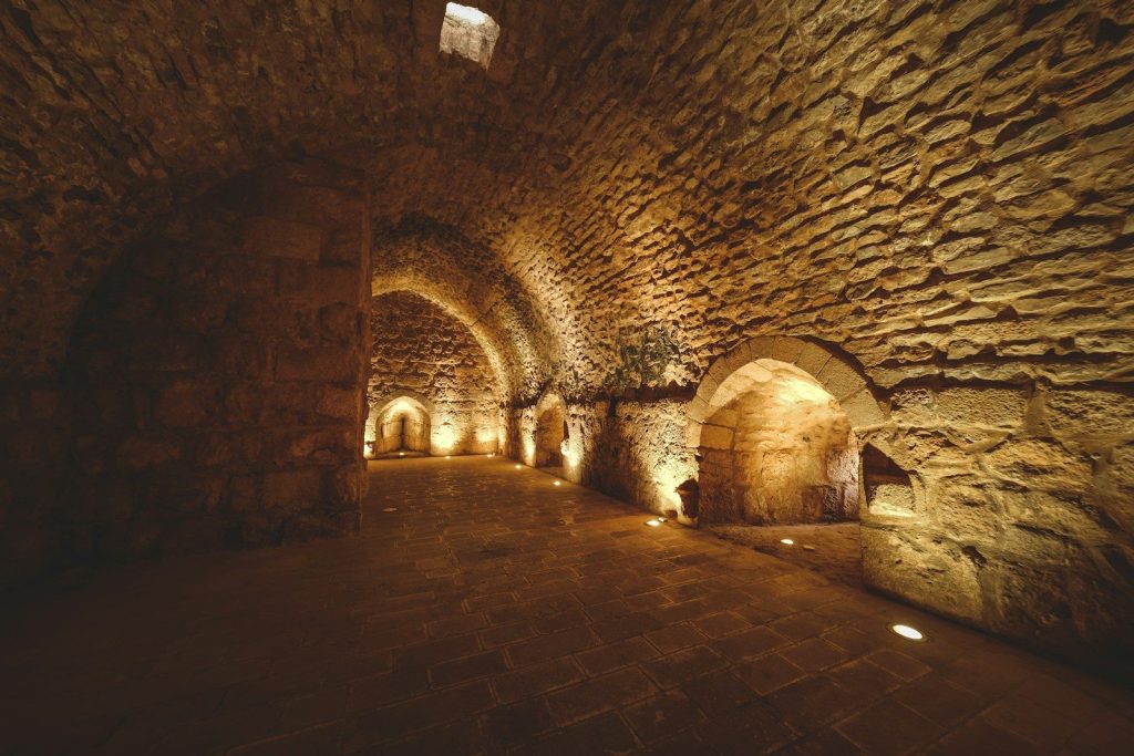a dimly lit tunnel with stone walls and cobblestones