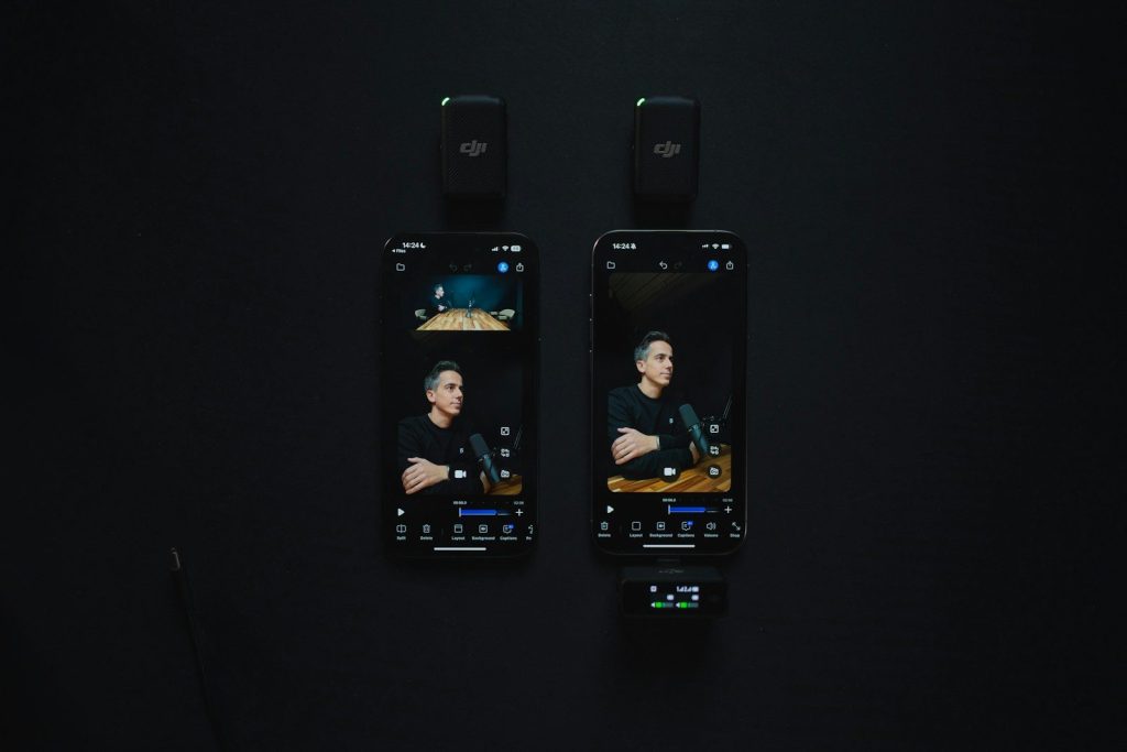 Two smartphones displaying video recordings next to microphones.