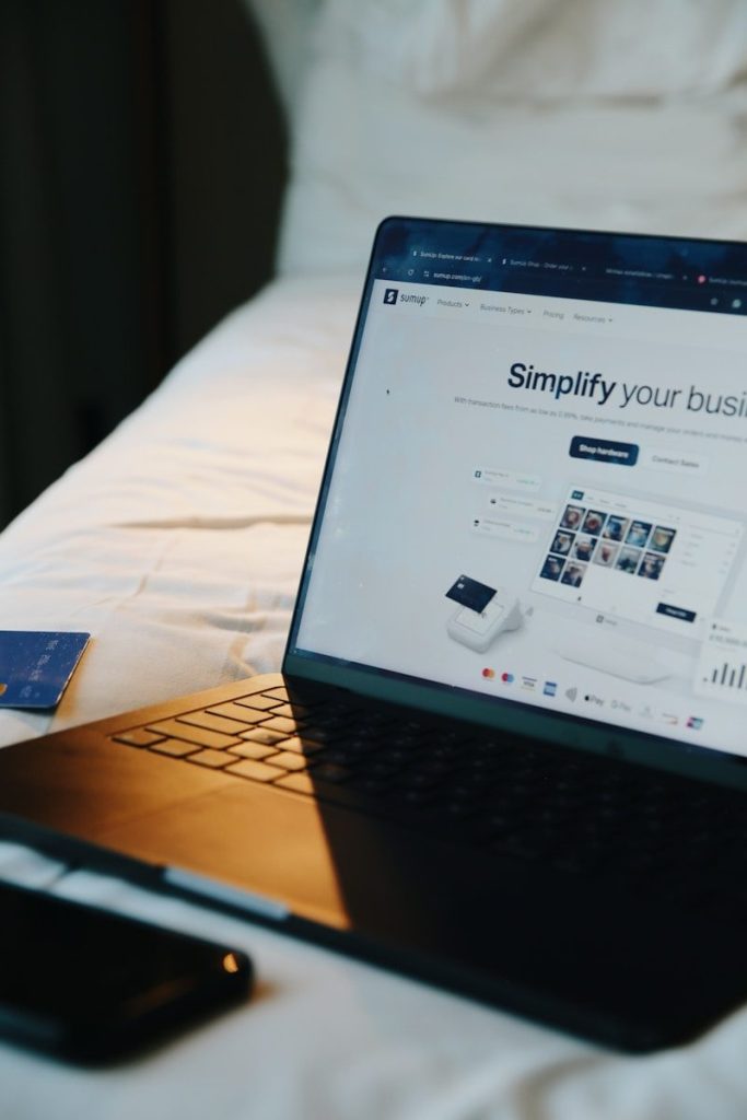Laptop, phone, and card on a bed.
