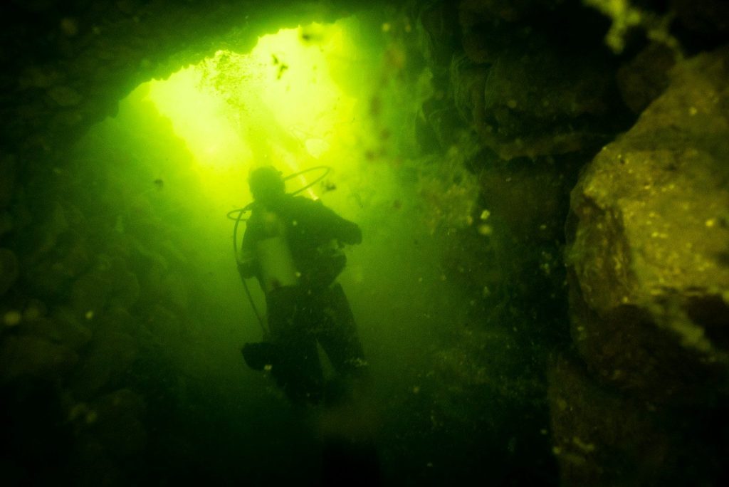 A scuba in a cave with a green light