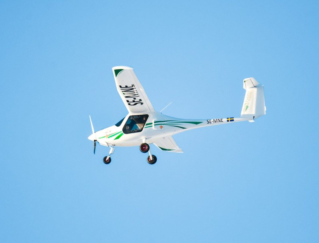 A small white airplane flying in a clear blue sky.