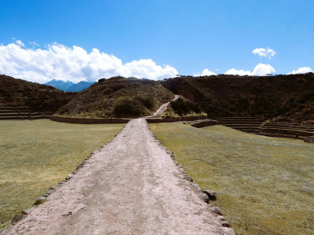 Path leading to ancient ruins under a blue sky.