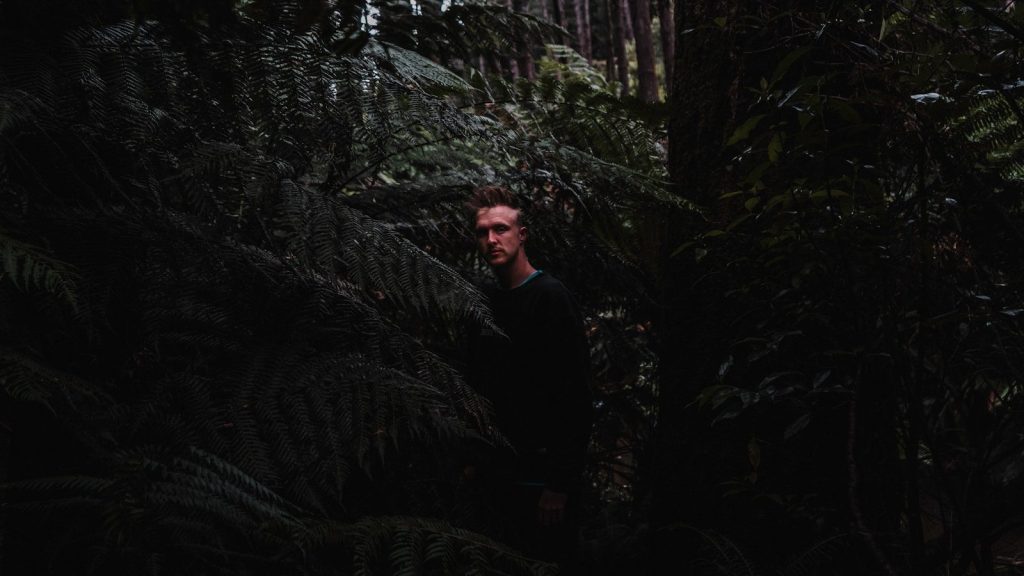 man in black long sleeve shirt standing beside green plant