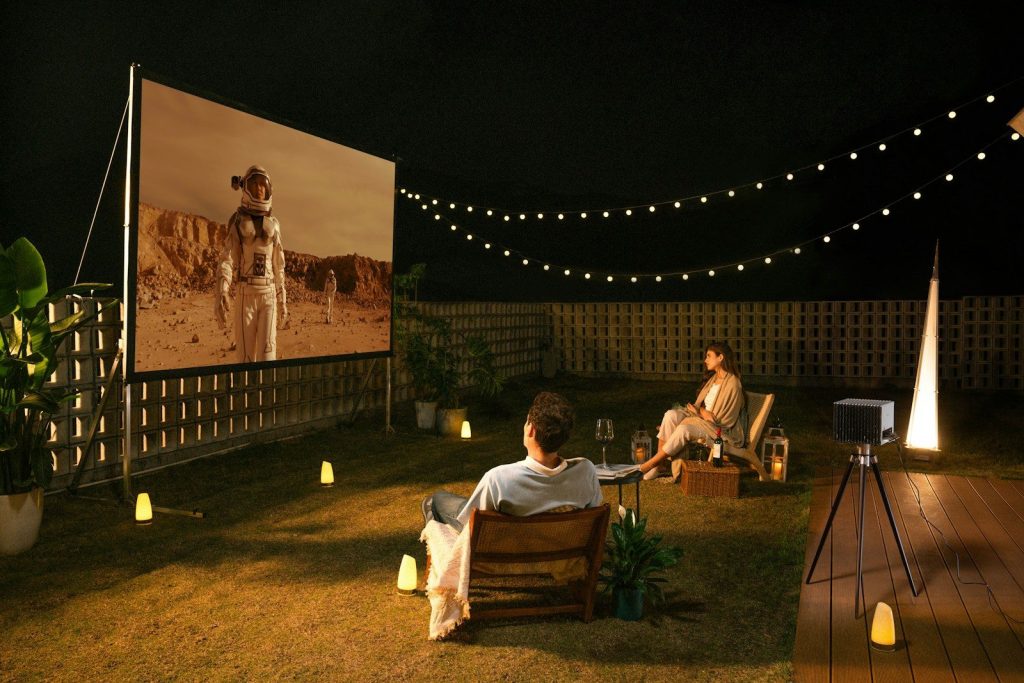 People watch a movie outdoors at night.