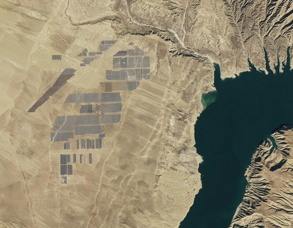 Aerial view of a large solar farm by a reservoir