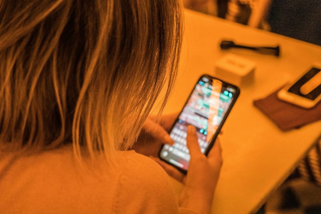 woman in white shirt holding black iphone 4