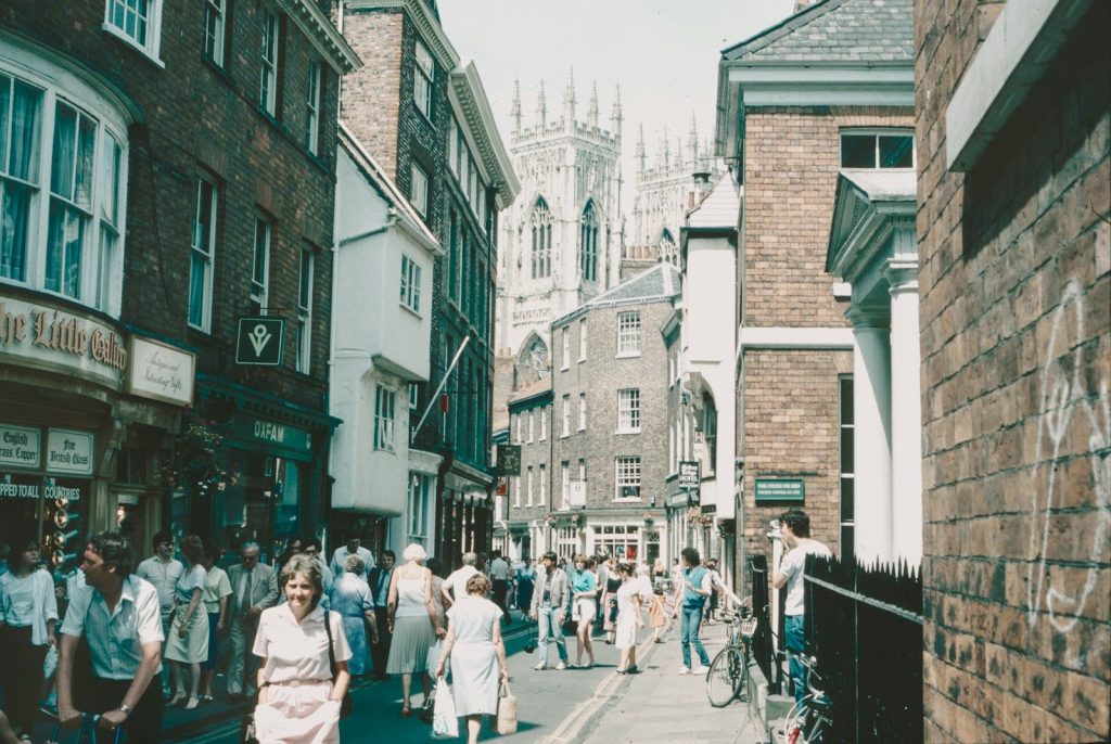 a group of people walking down a street next to tall buildings