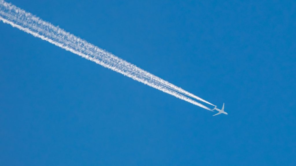 Airplane leaving a contrail across a clear blue sky