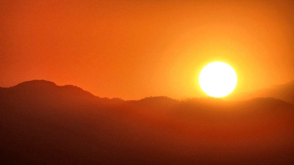the sun is setting over a mountain range