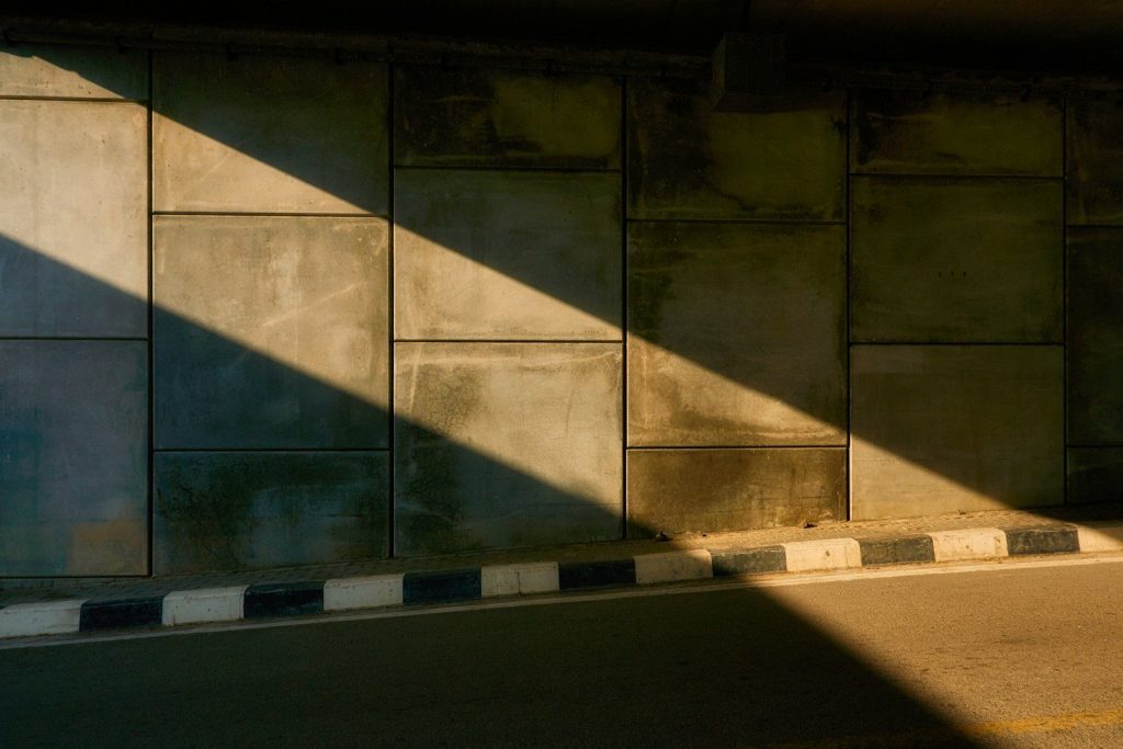 Sunlight casts a diagonal shadow on a concrete wall.