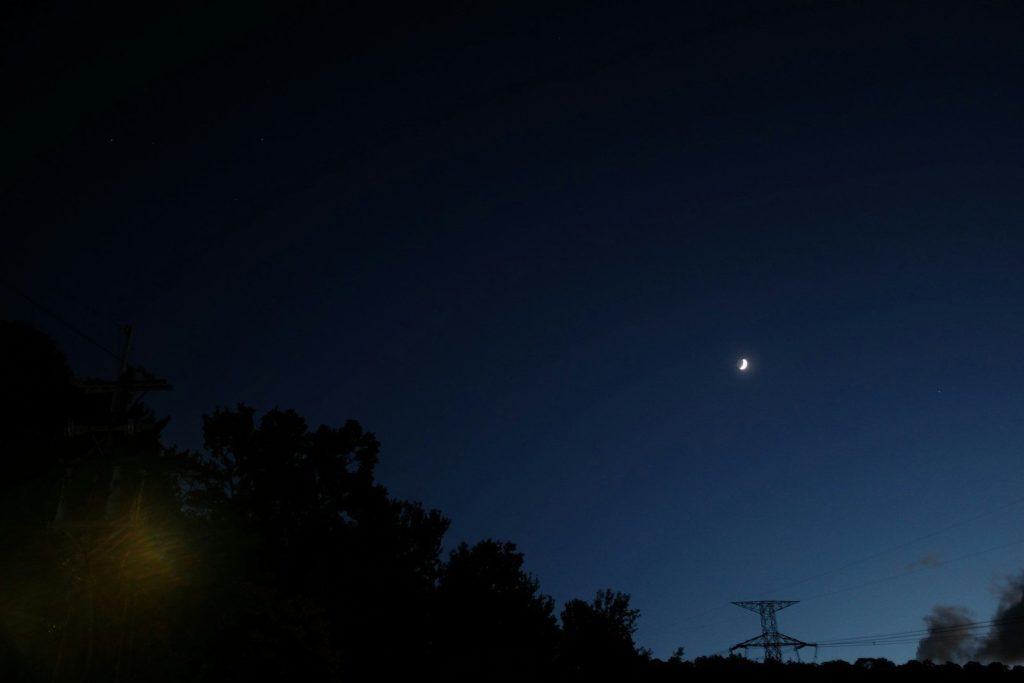 Crescent moon in a dark blue twilight sky.