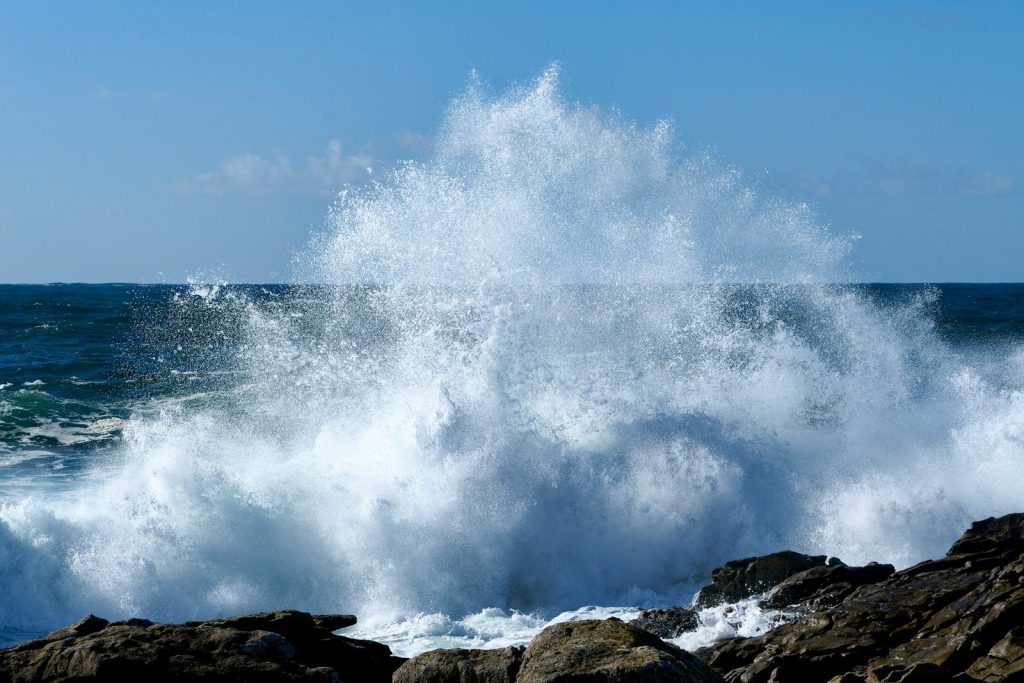 A large wave crashing over a rocky shore