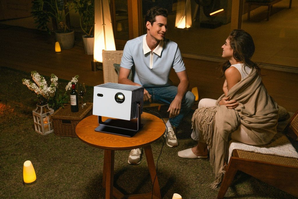 A couple enjoys a movie night outdoors with a projector.