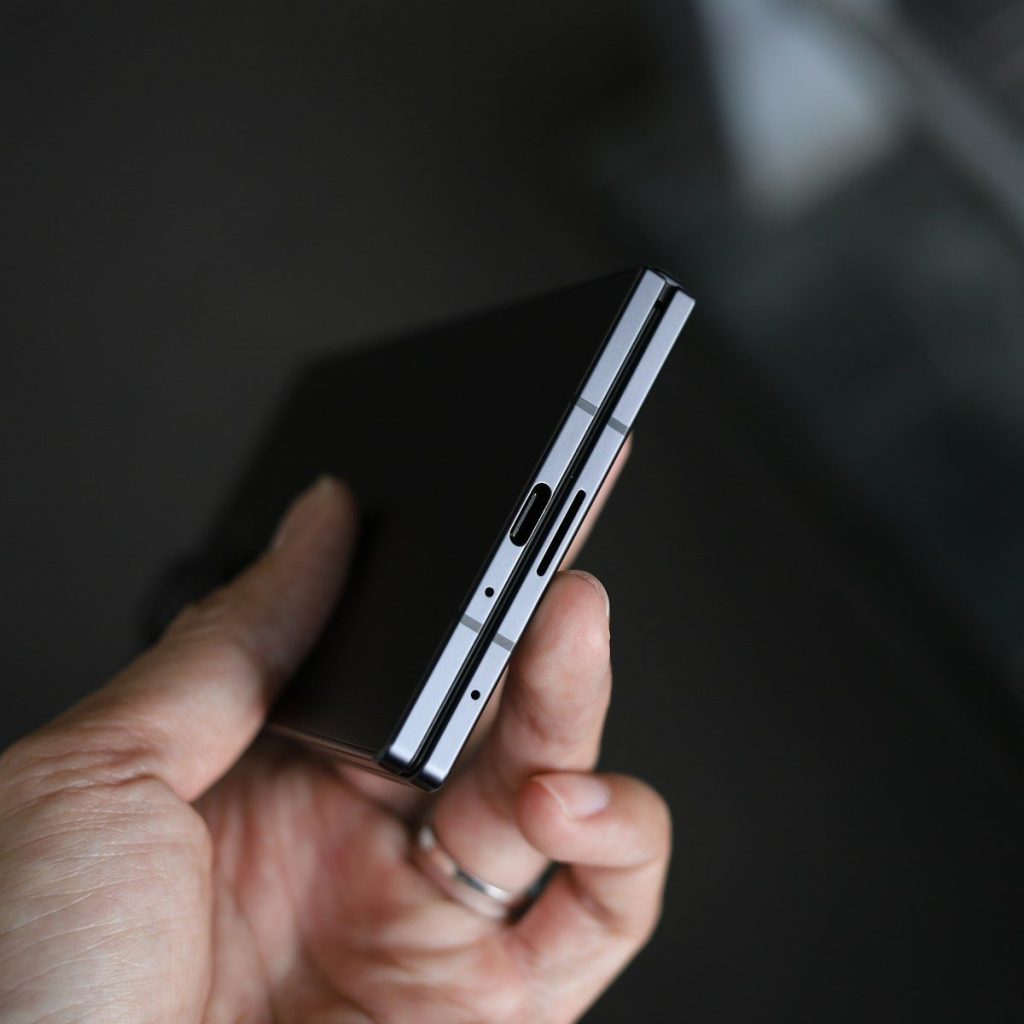 A hand holding a black smartphone with silver accents.