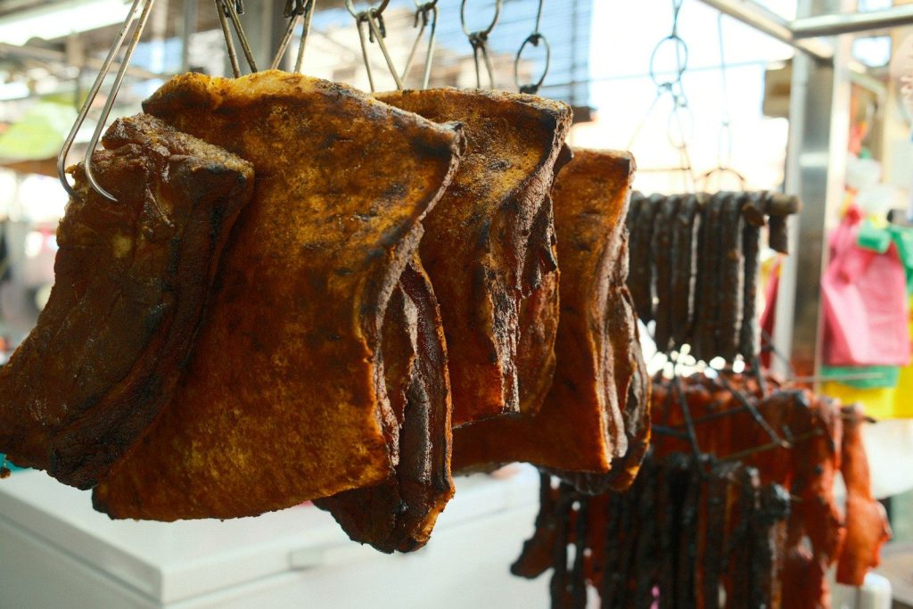 Several pieces of meat hanging from hooks in a market