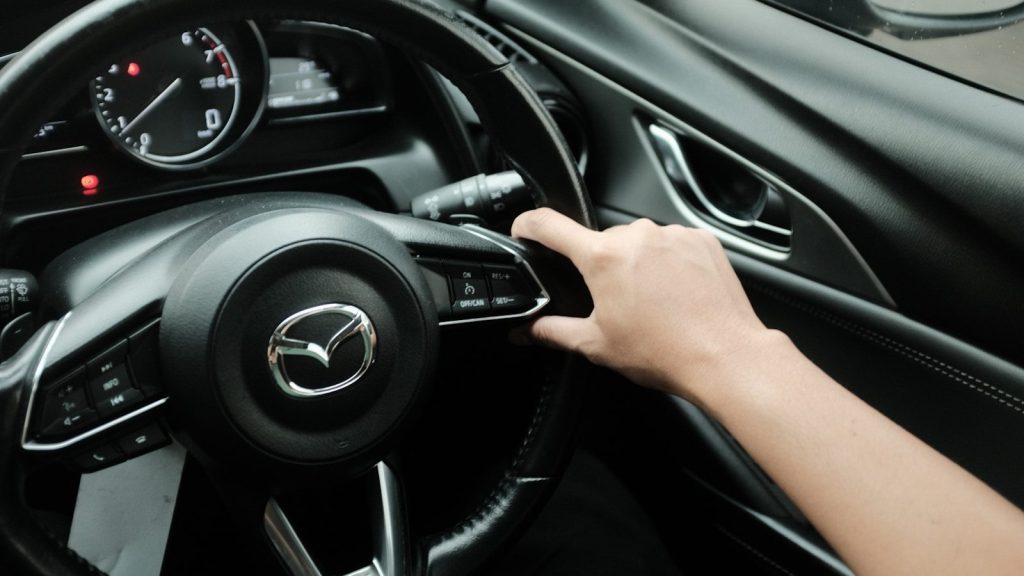 Hand pressing button on car steering wheel
