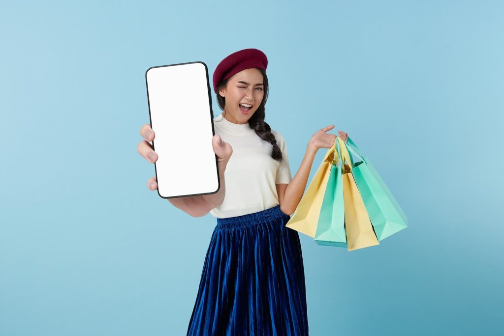 A woman holding a tablet computer and shopping bags