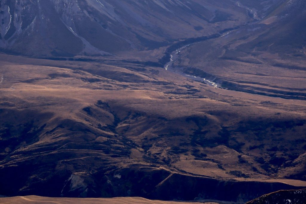 A winding river flows through a vast, dry mountain valley.