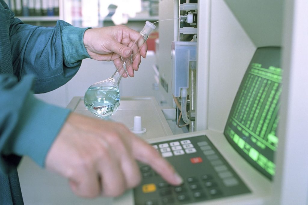 Close-up of a scientist operating lab equipment with a flask in hand.