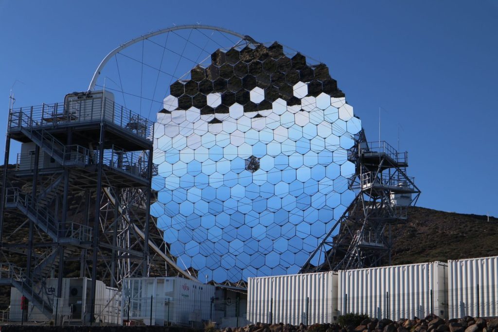 Futuristic reflective structure with hexagonal mirrors under a clear blue sky. Modern design.