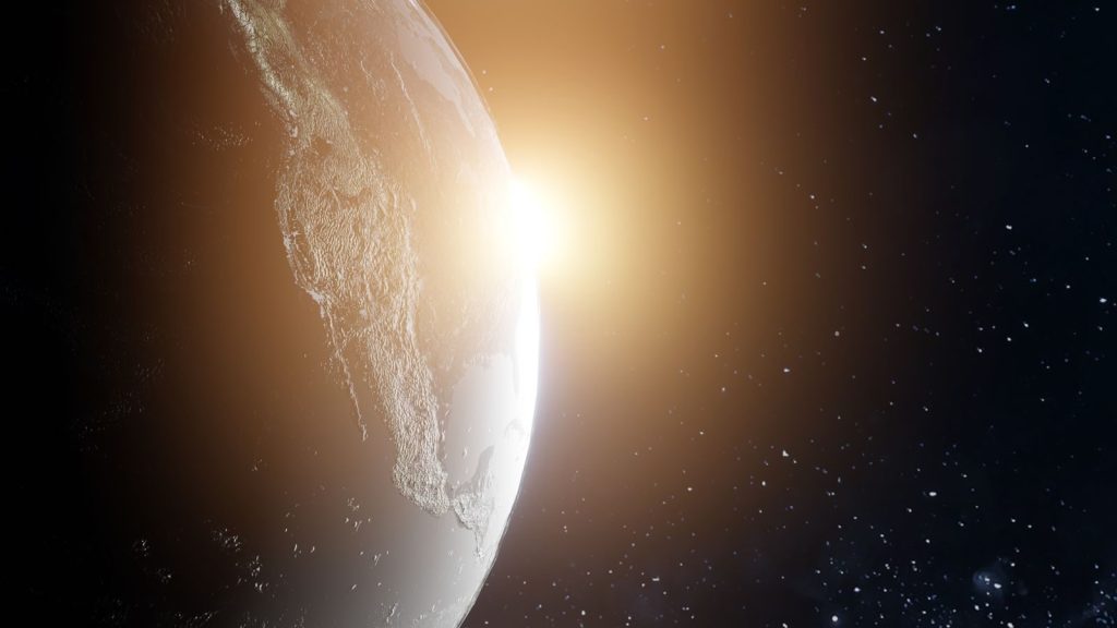A breathtaking view of Earth with the sun rising, illuminating the planet in space.