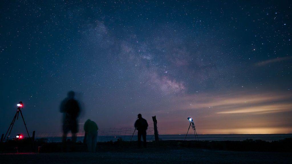 Captivating long exposure of stargazers under the Milky Way, showcasing the beauty of the night sky.