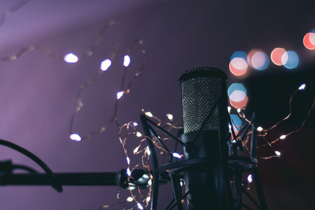 Condenser microphone surrounded by string lights creating a bokeh effect, ideal for studio and music themes.