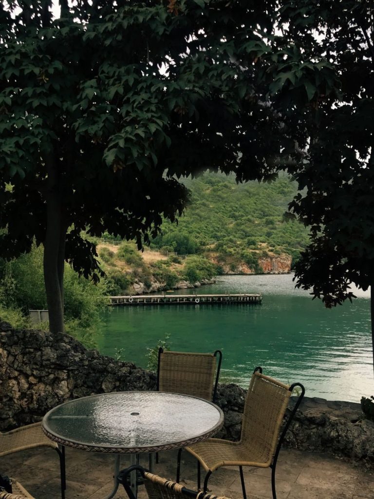 Tranquil lakeside scene with outdoor chairs and lush greenery, perfect for relaxation.