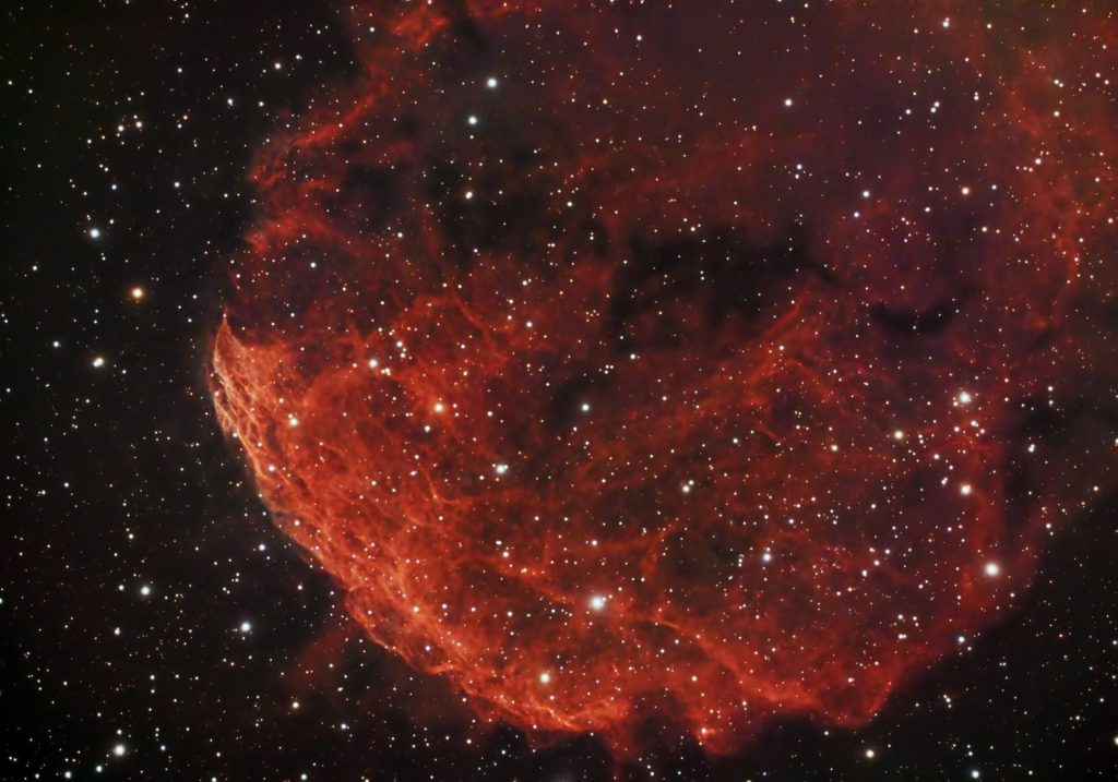 Dramatic view of the red Jellyfish Nebula amidst stars in the cosmos