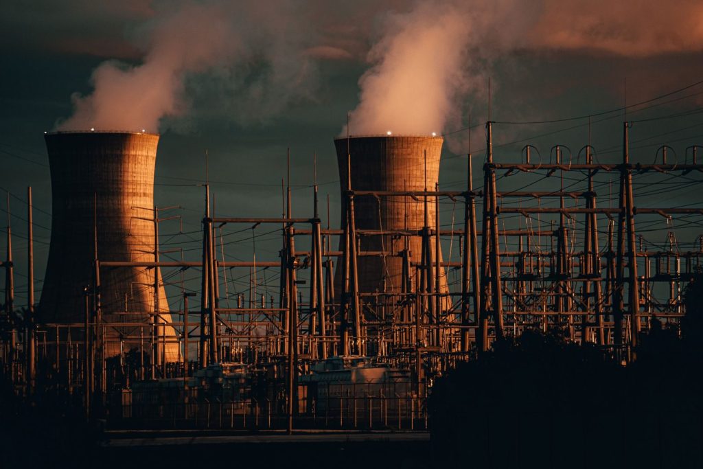 A nuclear power plant's cooling towers emit steam at sunset, highlighting industrial infrastructure.