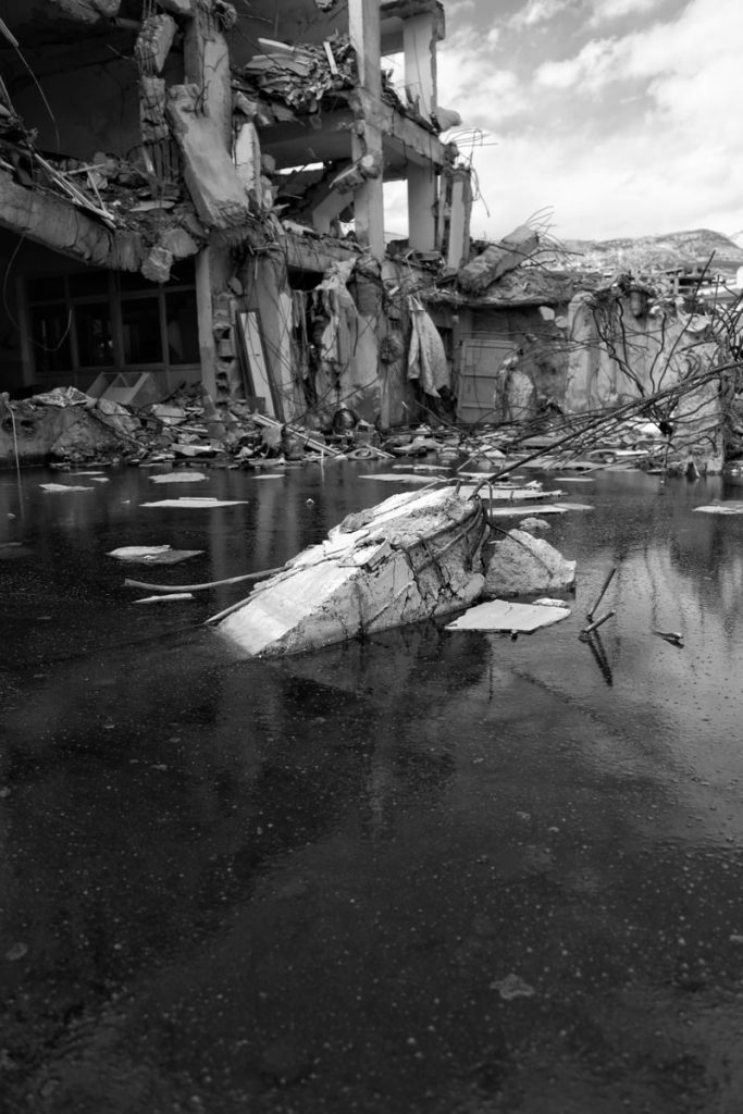 Black and white photo of a flooded, heavily damaged building in ruins.