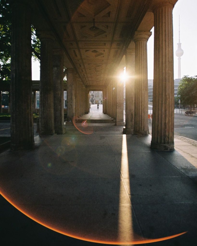 Sunset view through historic columns in Berlin, featuring the TV Tower.