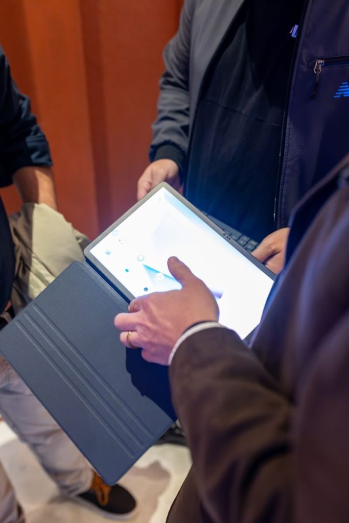 Close-up of people using a tablet with touchscreen interaction in an indoor setting.