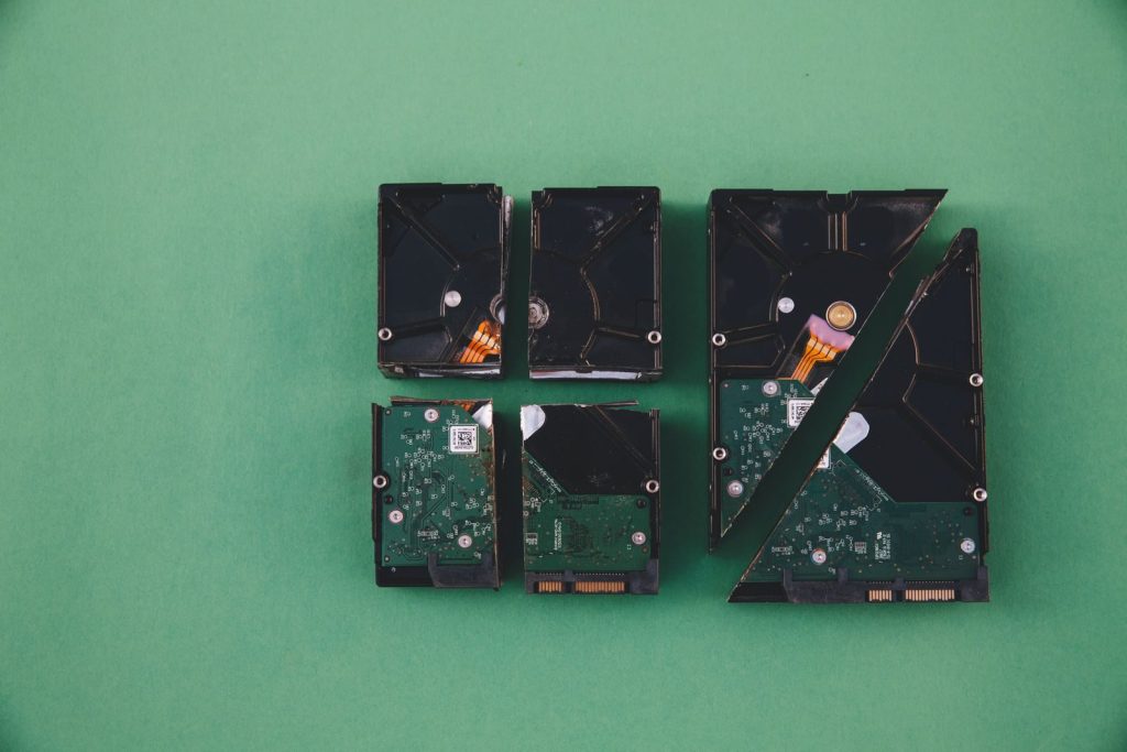 Four broken hard drives arranged on a green background, showcasing data destruction.