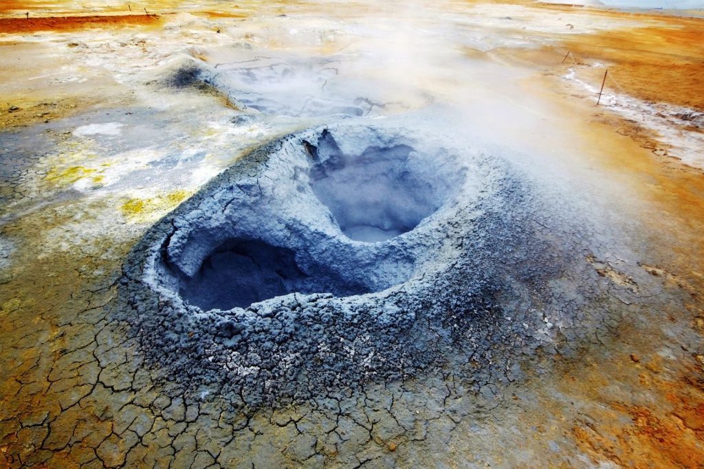 A captivating geothermal landscape featuring a steaming hot spring with vibrant colors and geological formations.