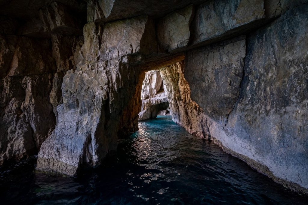 Explore a tranquil limestone cave with shimmering water reflections in a serene atmosphere.