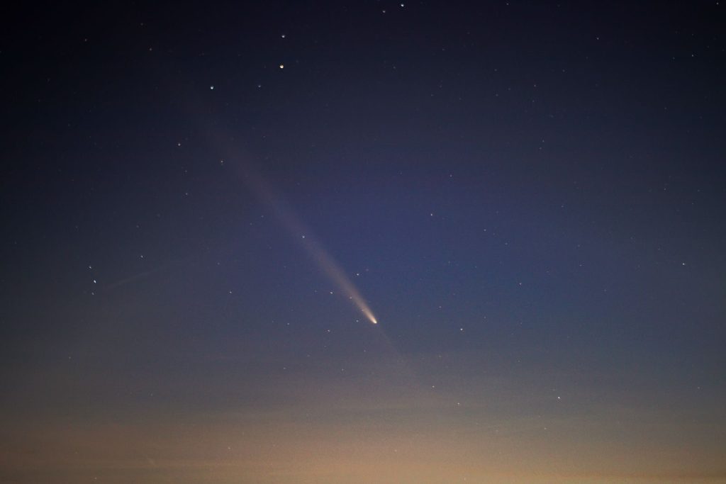Captivating view of a comet streaking across the night sky with twinkling stars.